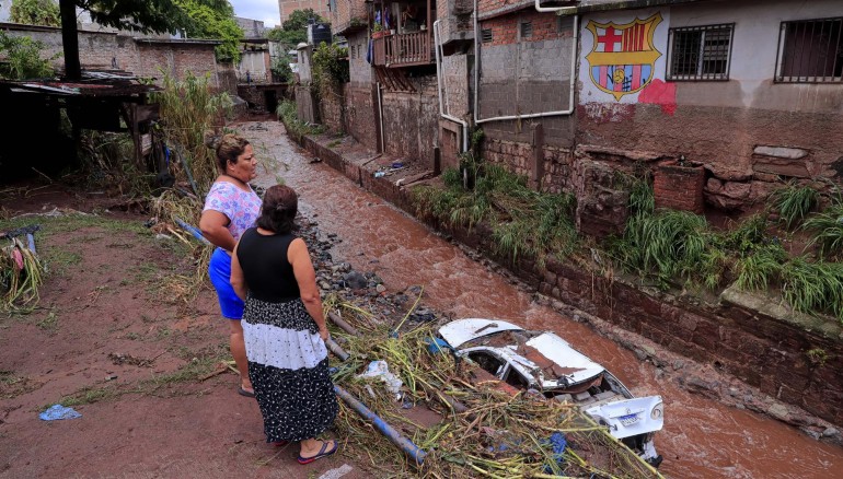 Dos mujeres observan un auto arrastrado hoy, debido al desbordamiento de una quebrada en Tegucigalpa (Honduras). EFE
