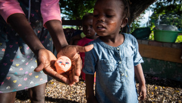 Fotografía tomada el pasado 27 de agosto en la que se registraron las manos de una mujer al mostrale a una niña la cabeza de un muñeco viejo, mientras se refugian en un parque luego de ser desplazadas por el enfrentamiento de bandas de delincuentes, en Puerto Príncipe (Haití). EFE/Johnson Sabin