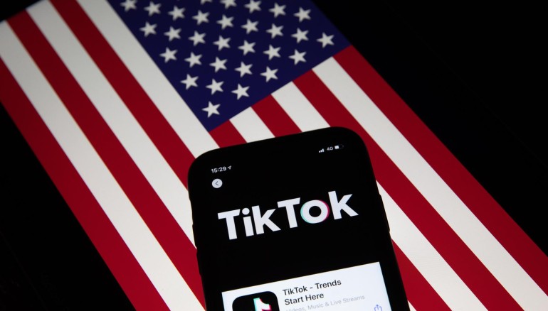 Fotografía de archivo que muestra la aplicación TikTok en la pantalla de un teléfono celular, con la bandera estadounidense de fondo. EFE/Roman Pilipey