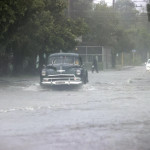 Un auto clásico pasa por una calle llena de agua en Cuba, en una fotografía de archivo. EFE/Ernesto Mastrascusa