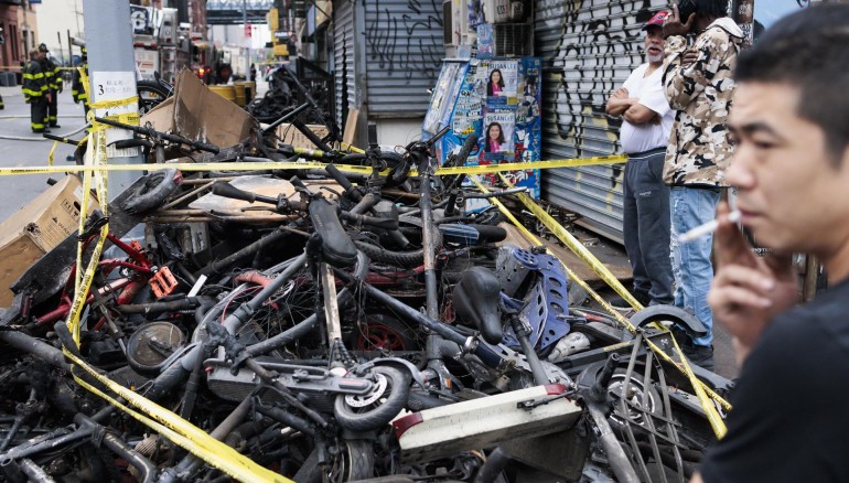 Personas observan un montón de bicicletas eléctricas quemadas cerca del lugar donde se produjo un incendio nocturno en Nueva York, este 20 de junio de 2023. EFE/EPA/Justin Lane