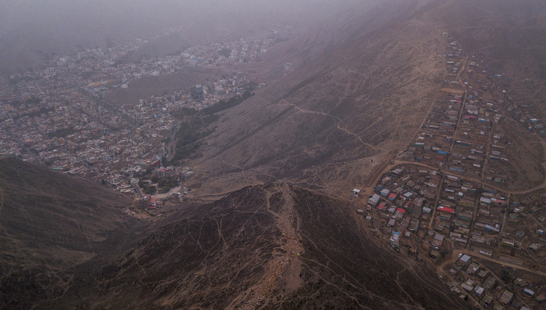 LIM01. LIMA (PERÚ), 05/09/2023.-Vista aérea del distrito Villa del Triunfo hoy, en Lima (Perú). El denominado "muro de la vergüenza" de Lima, que separa a una humilde barriada de un distrito adinerado en la capital peruana, ha comenzado a ser demolido por orden del Tribunal Constitucional, una medida que ha suscitado comentarios de distinto signo a cada lado y que no cierra la brecha social abierta. El muro, en cuyo derribo trabajan operarios desde hace varios días, se ubica en lo alto de una loma que marca el límite entre el acomodado distrito de La Molina y el popular Villa del Triunfo, en pleno parque ecológico. EFE/ Aldair Mejía